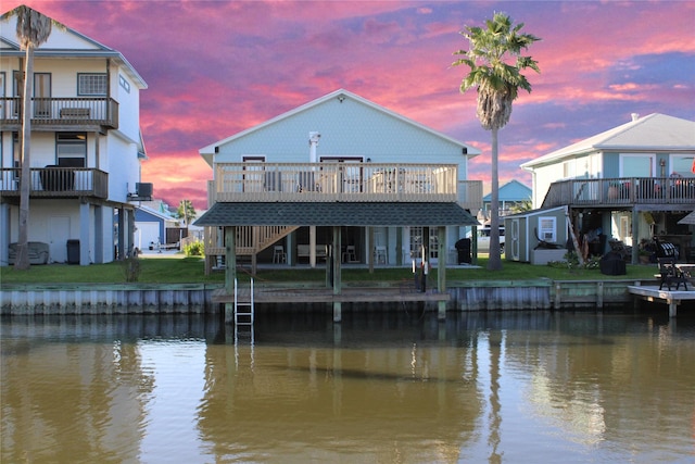 back house at dusk featuring a deck with water view