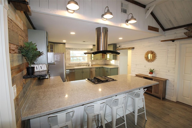 kitchen featuring kitchen peninsula, appliances with stainless steel finishes, island range hood, a breakfast bar area, and wood walls