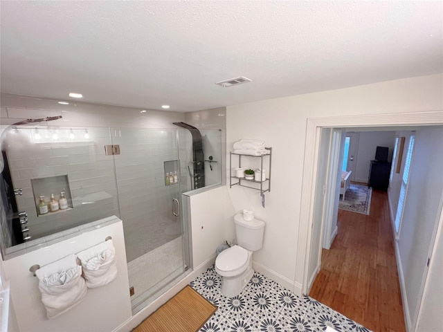 bathroom with wood-type flooring, toilet, a shower with shower door, and a textured ceiling