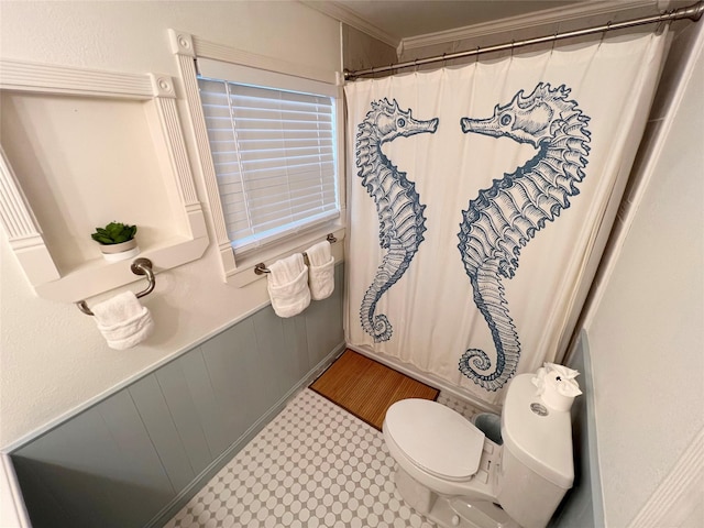 bathroom with toilet, crown molding, and wooden walls