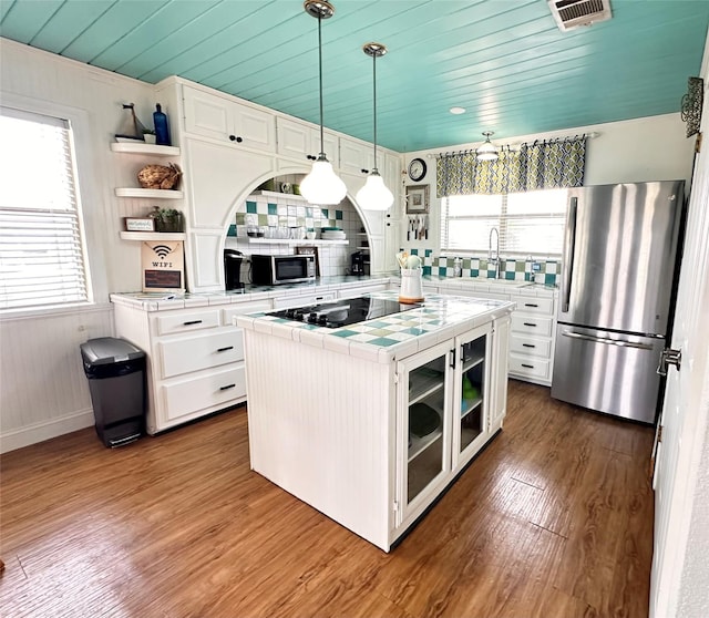 kitchen with stainless steel appliances, tile countertops, decorative light fixtures, dark hardwood / wood-style floors, and white cabinetry