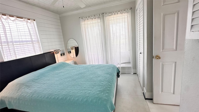 bedroom featuring wooden walls, multiple windows, ornamental molding, and ceiling fan