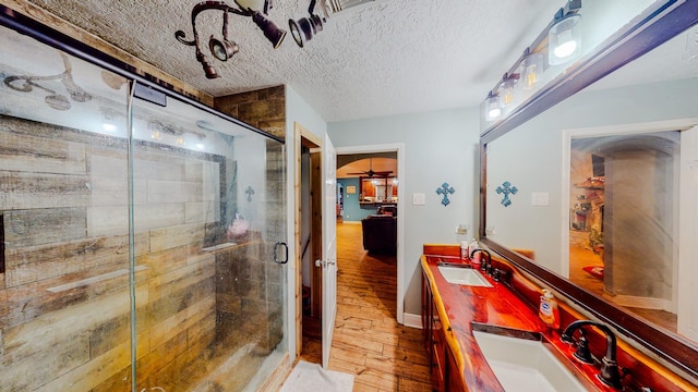 bathroom featuring vanity, hardwood / wood-style floors, a textured ceiling, and a shower with shower door