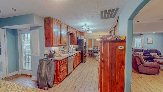 kitchen with stainless steel appliances, a wealth of natural light, and light hardwood / wood-style flooring