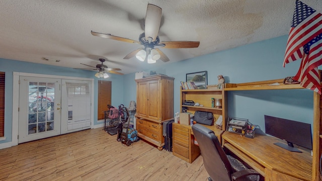 home office with ceiling fan, french doors, light hardwood / wood-style floors, and a textured ceiling