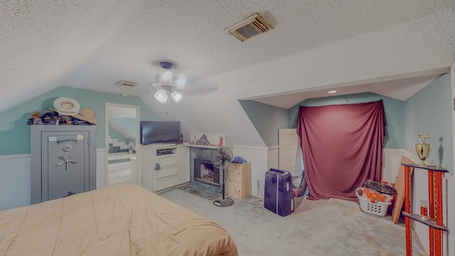 carpeted bedroom with ceiling fan, a fireplace, lofted ceiling, and a textured ceiling