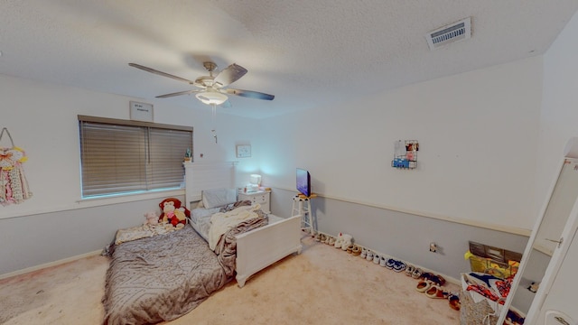 carpeted bedroom with ceiling fan and a textured ceiling