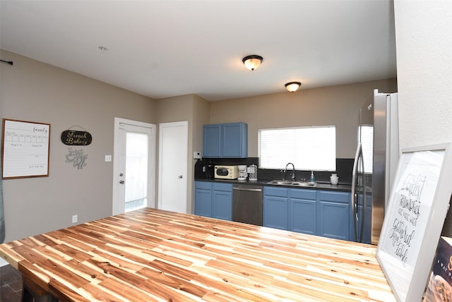 kitchen with sink, blue cabinets, and appliances with stainless steel finishes