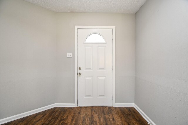 foyer entrance with a textured ceiling and dark hardwood / wood-style floors