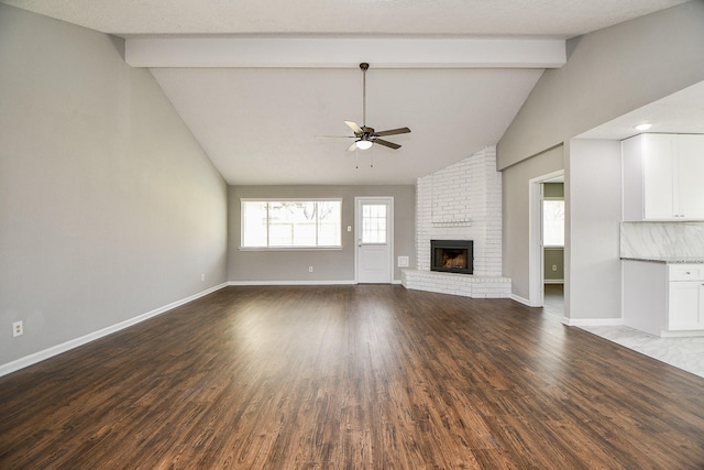 unfurnished living room with lofted ceiling with beams, ceiling fan, a textured ceiling, a fireplace, and wood-type flooring