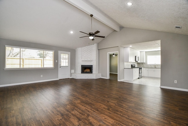 unfurnished living room with hardwood / wood-style floors, vaulted ceiling with beams, ceiling fan, a fireplace, and a textured ceiling