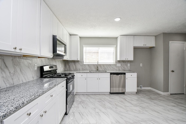 kitchen with backsplash, sink, light stone countertops, white cabinetry, and stainless steel appliances