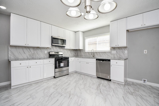 kitchen with light stone counters, white cabinets, and appliances with stainless steel finishes