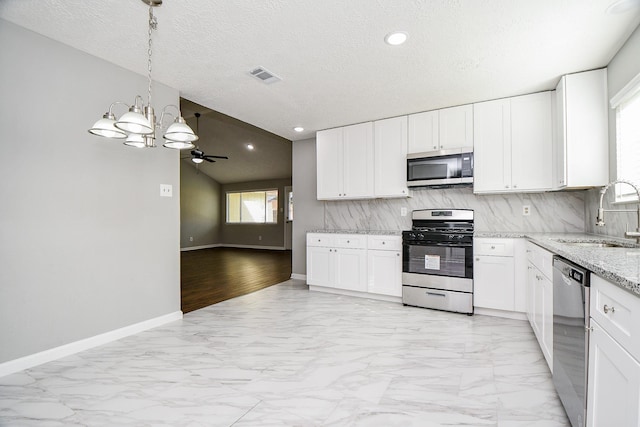 kitchen with a textured ceiling, ceiling fan with notable chandelier, stainless steel appliances, sink, and white cabinets