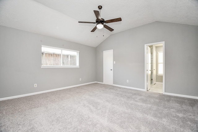 spare room with a textured ceiling, light colored carpet, ceiling fan, and lofted ceiling