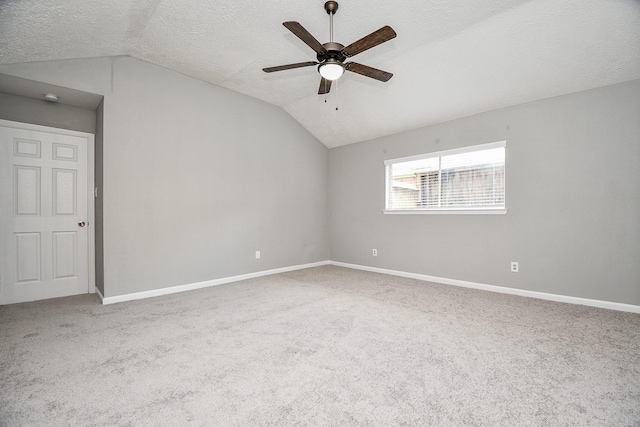 empty room with carpet flooring, ceiling fan, a textured ceiling, and vaulted ceiling