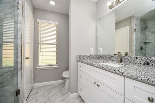 bathroom with a textured ceiling, vanity, toilet, and a shower with door