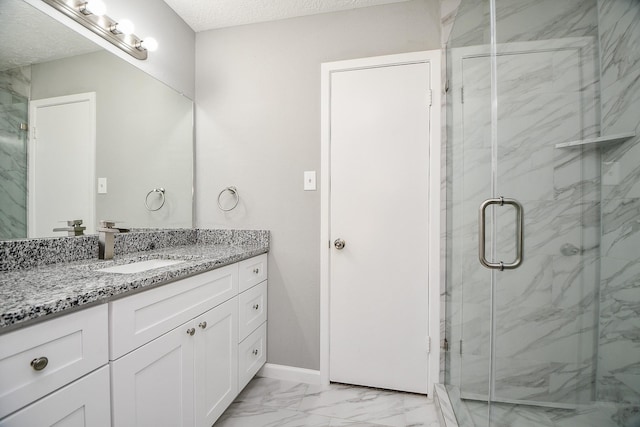 bathroom with vanity, a shower with shower door, and a textured ceiling