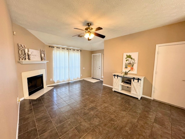 unfurnished living room with ceiling fan, dark tile patterned floors, a textured ceiling, and lofted ceiling