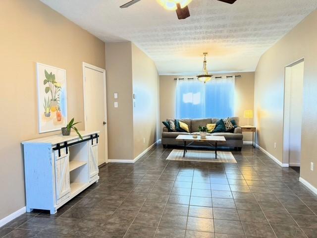 tiled living room featuring ceiling fan and a textured ceiling