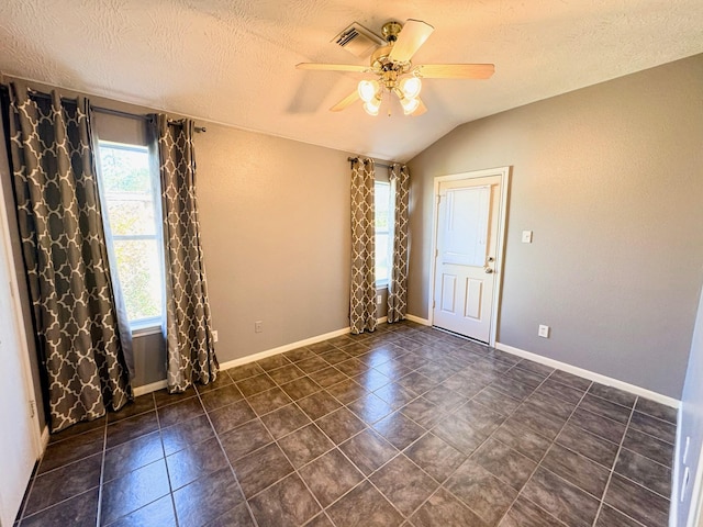 spare room with a textured ceiling, ceiling fan, plenty of natural light, and lofted ceiling