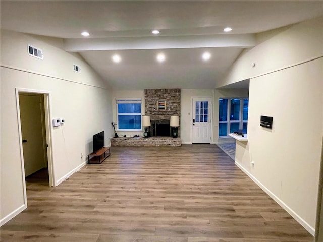 unfurnished living room with vaulted ceiling with beams, a fireplace, and hardwood / wood-style floors