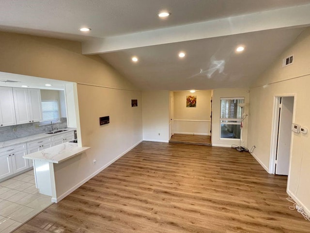 unfurnished living room featuring light hardwood / wood-style flooring, vaulted ceiling, and sink