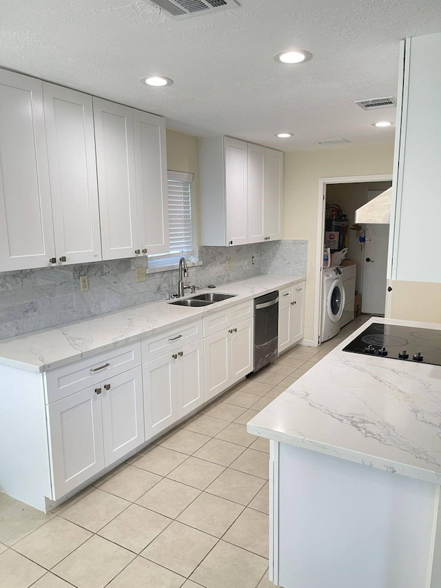 kitchen featuring a textured ceiling, sink, electric cooktop, washing machine and dryer, and white cabinetry