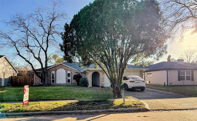 ranch-style home with a front yard, brick siding, a garage, and driveway