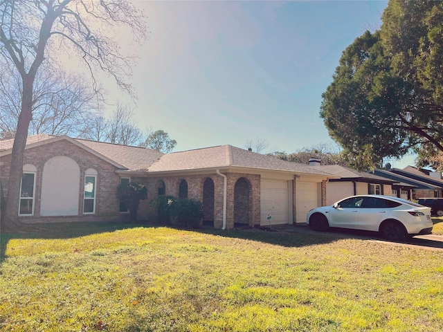 single story home featuring brick siding, an attached garage, a front yard, and roof with shingles