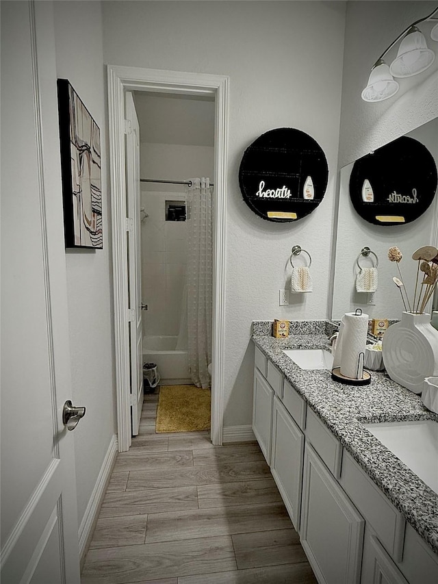 bathroom with hardwood / wood-style flooring, vanity, and shower / bathtub combination with curtain