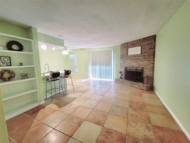 tiled living room with ceiling fan, sink, built in features, a wood stove, and a textured ceiling