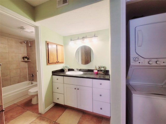 full bathroom featuring tiled shower / bath combo, tile patterned flooring, stacked washer / drying machine, vanity, and toilet