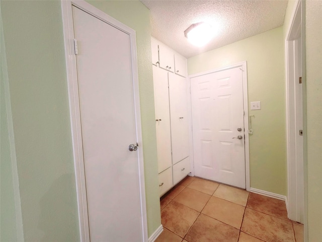 doorway to outside featuring a textured ceiling and light tile patterned flooring