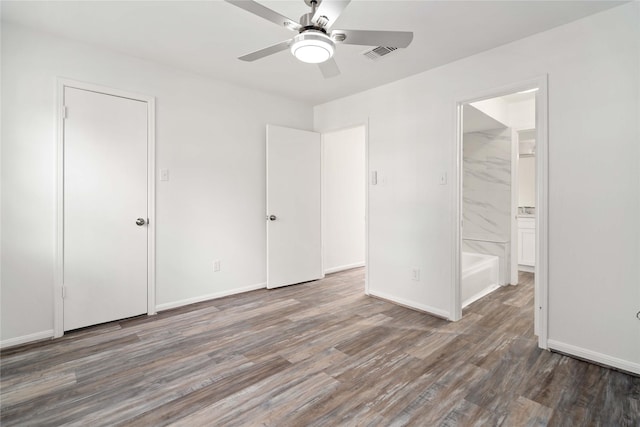 unfurnished bedroom with ensuite bathroom, ceiling fan, and dark wood-type flooring