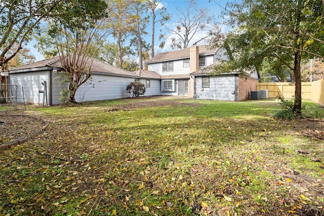 rear view of property featuring a lawn and cooling unit