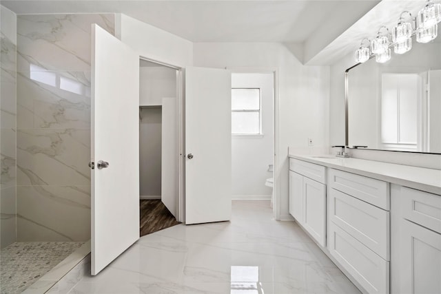 bathroom with a tile shower, vanity, and toilet