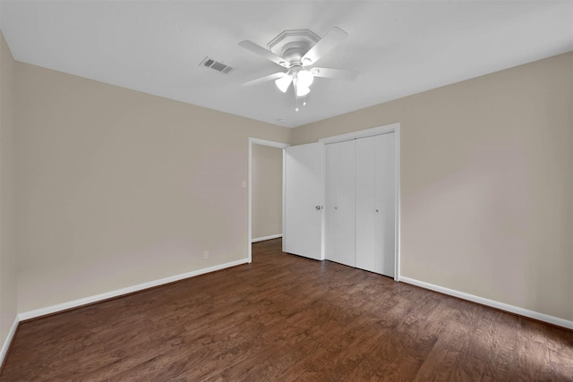 unfurnished bedroom with ceiling fan, dark wood-type flooring, and a closet