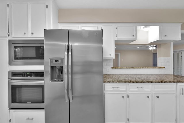 kitchen with ceiling fan, dark stone countertops, decorative backsplash, white cabinets, and appliances with stainless steel finishes