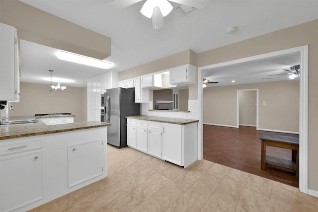 kitchen featuring white cabinets, sink, stainless steel refrigerator with ice dispenser, kitchen peninsula, and a chandelier