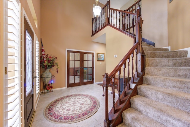 tiled entrance foyer with a healthy amount of sunlight, a towering ceiling, and french doors