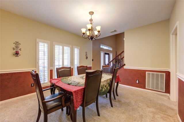 carpeted dining area featuring a chandelier