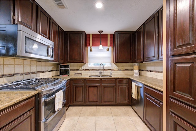 kitchen with backsplash, sink, light tile patterned floors, appliances with stainless steel finishes, and decorative light fixtures