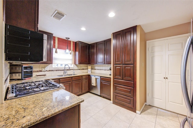 kitchen featuring pendant lighting, sink, tasteful backsplash, light stone counters, and stainless steel appliances