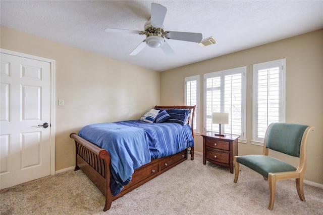 bedroom with light carpet, a textured ceiling, and ceiling fan