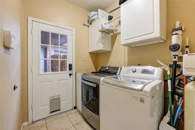 clothes washing area with washer and dryer, light tile patterned floors, cabinets, and a textured ceiling