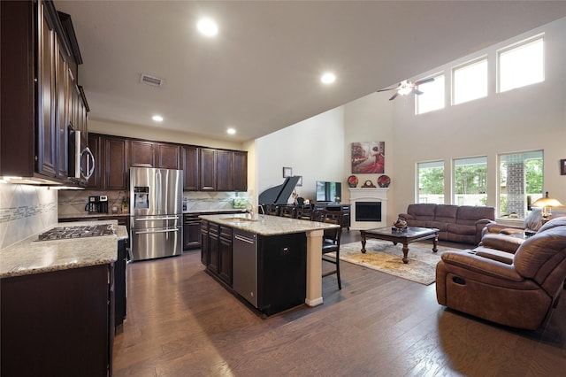 kitchen with a kitchen breakfast bar, dark wood-type flooring, a kitchen island, and stainless steel appliances