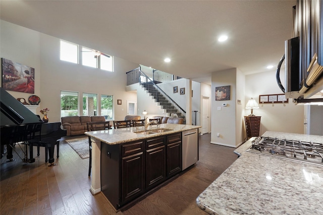 kitchen featuring sink, stainless steel appliances, dark hardwood / wood-style flooring, a breakfast bar, and a center island with sink