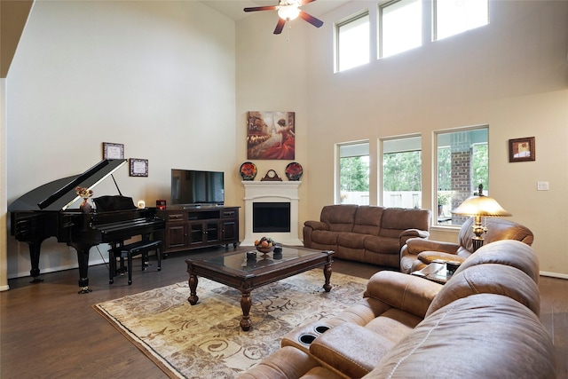 living room with ceiling fan, dark hardwood / wood-style flooring, and a towering ceiling