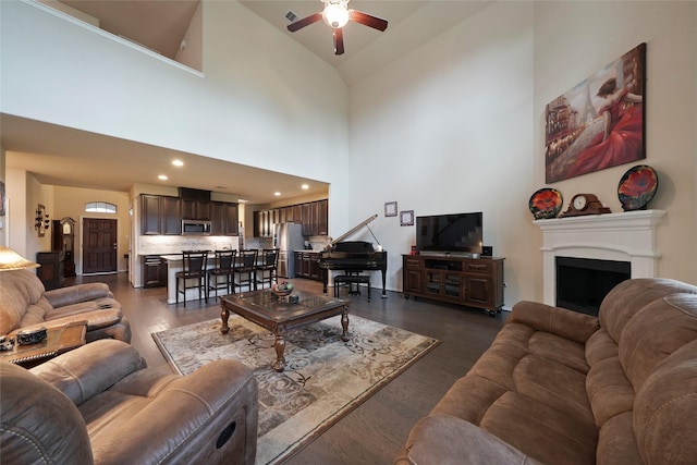 living room with ceiling fan, dark wood-type flooring, and high vaulted ceiling